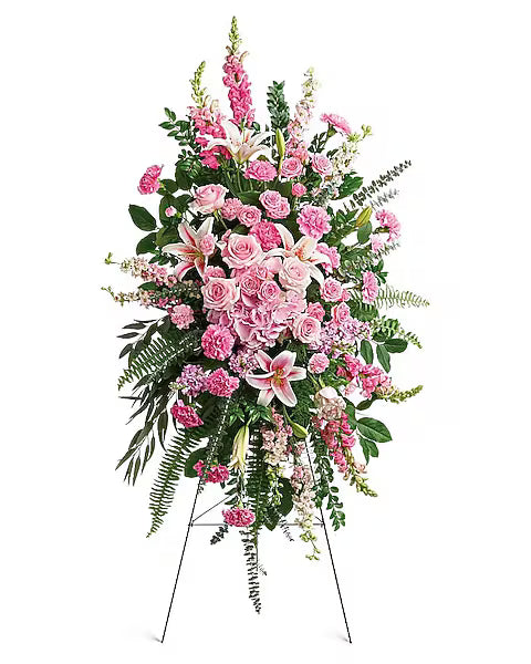 A large standing spray of funeral flowers made of a variety of pink flowers.