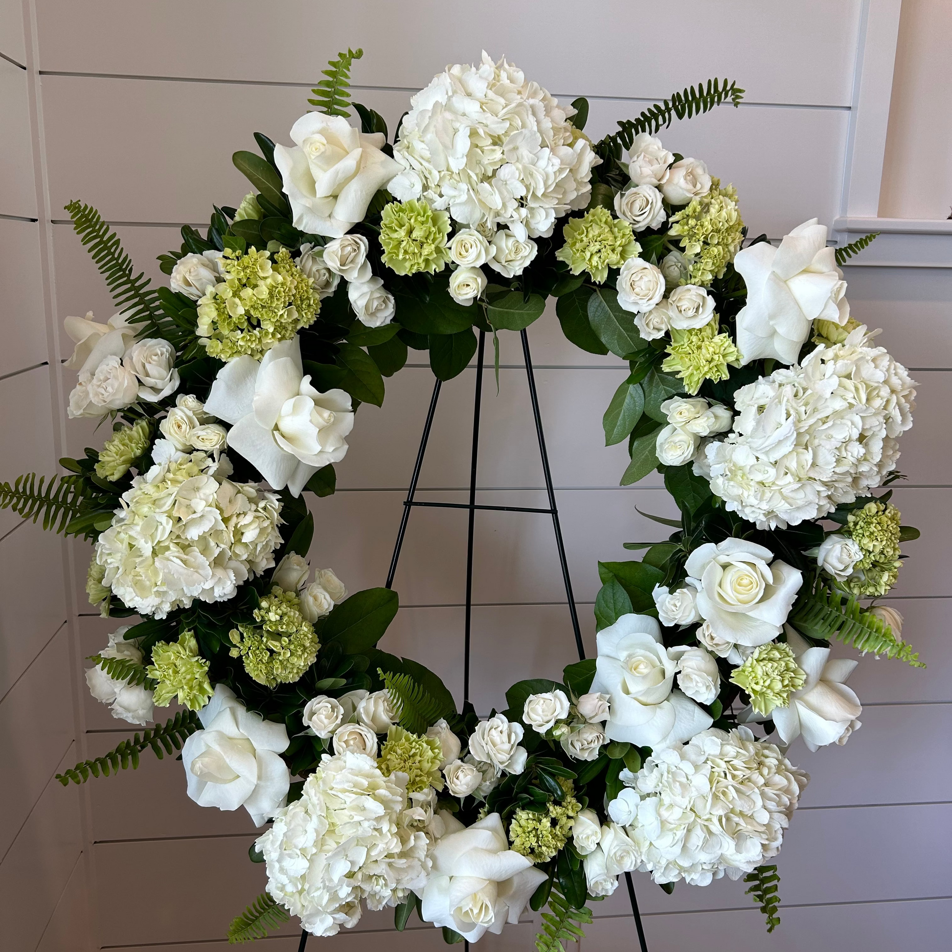 A floral wreath made of green and white flowers for a standing funeral spray.
