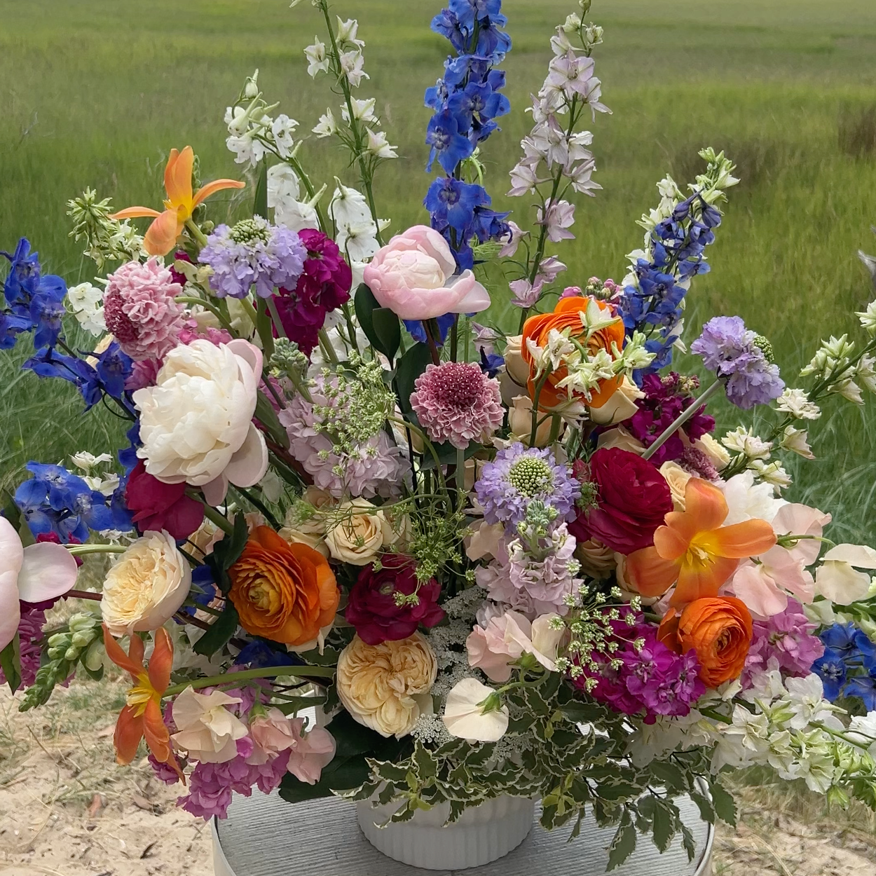 An extra large flower arrangement with pink, blue, orange, and white flowers. 