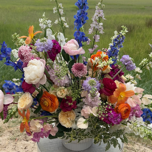 An extra large flower arrangement with pink, blue, orange, and white flowers. 