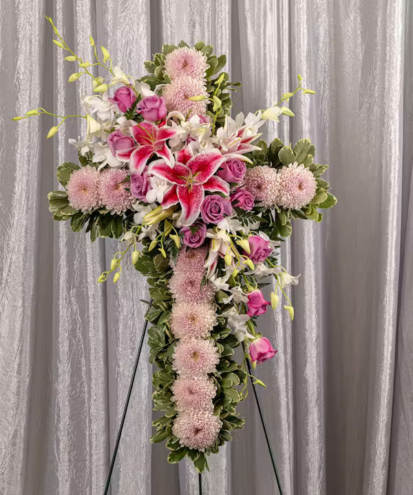 Floral cross arrangement with pink and white flowers on a gray background