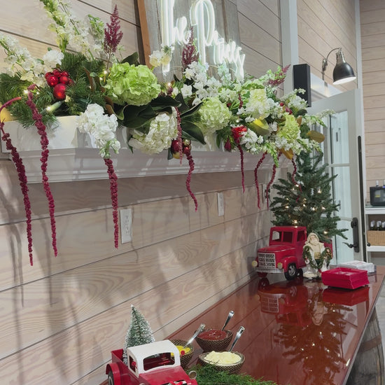 A mantle decorated with red, white, and green Christmas flowers.