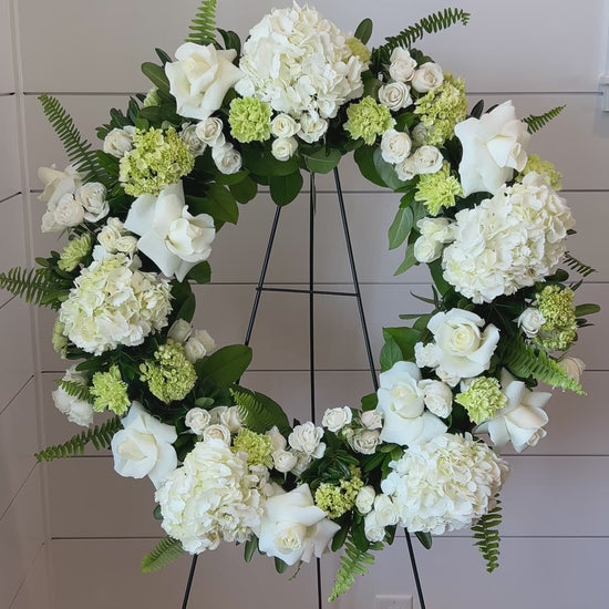 A floral wreath made of green and white flowers for a standing funeral spray.