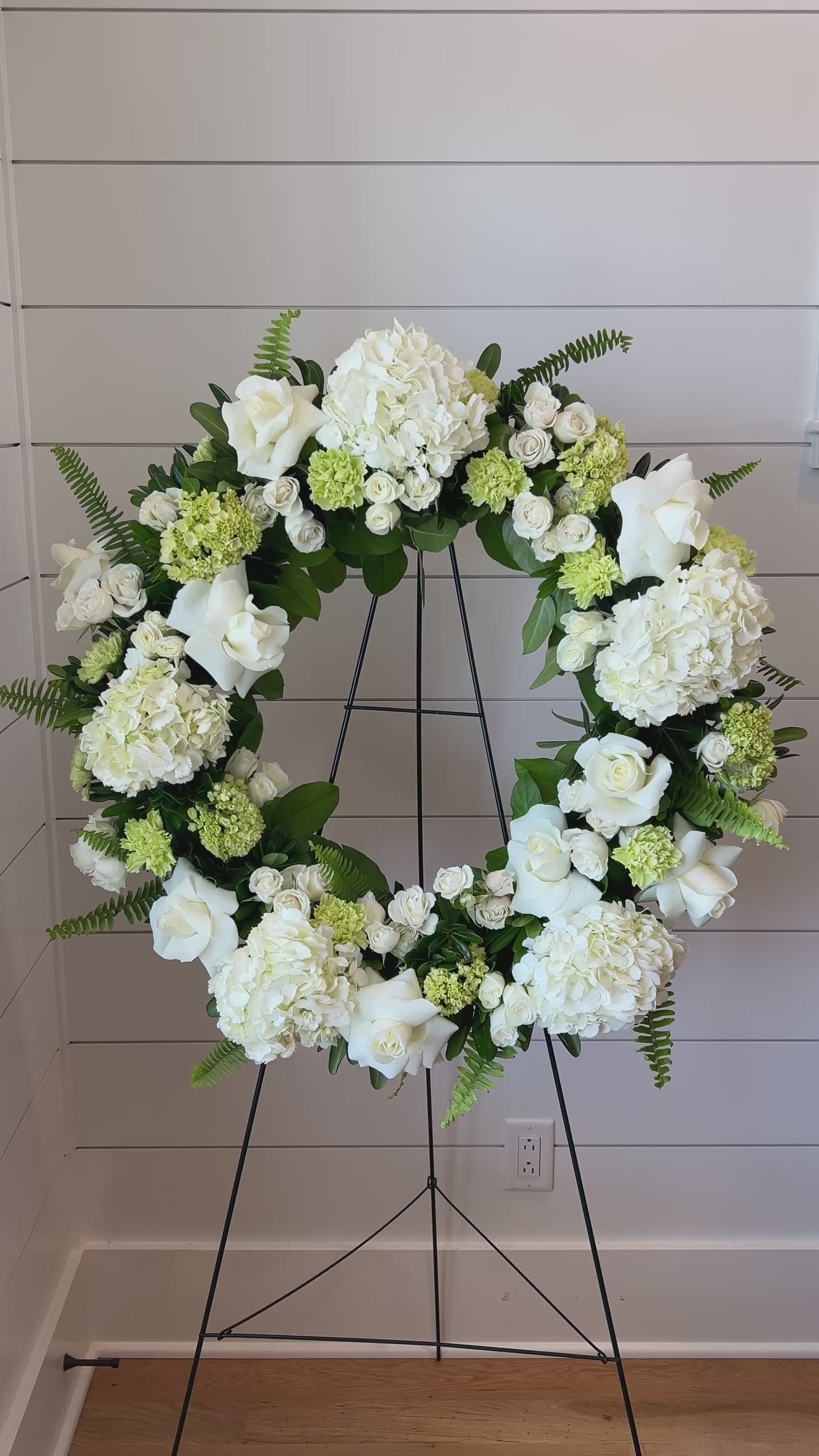 A floral wreath made of green and white flowers for a standing funeral spray.