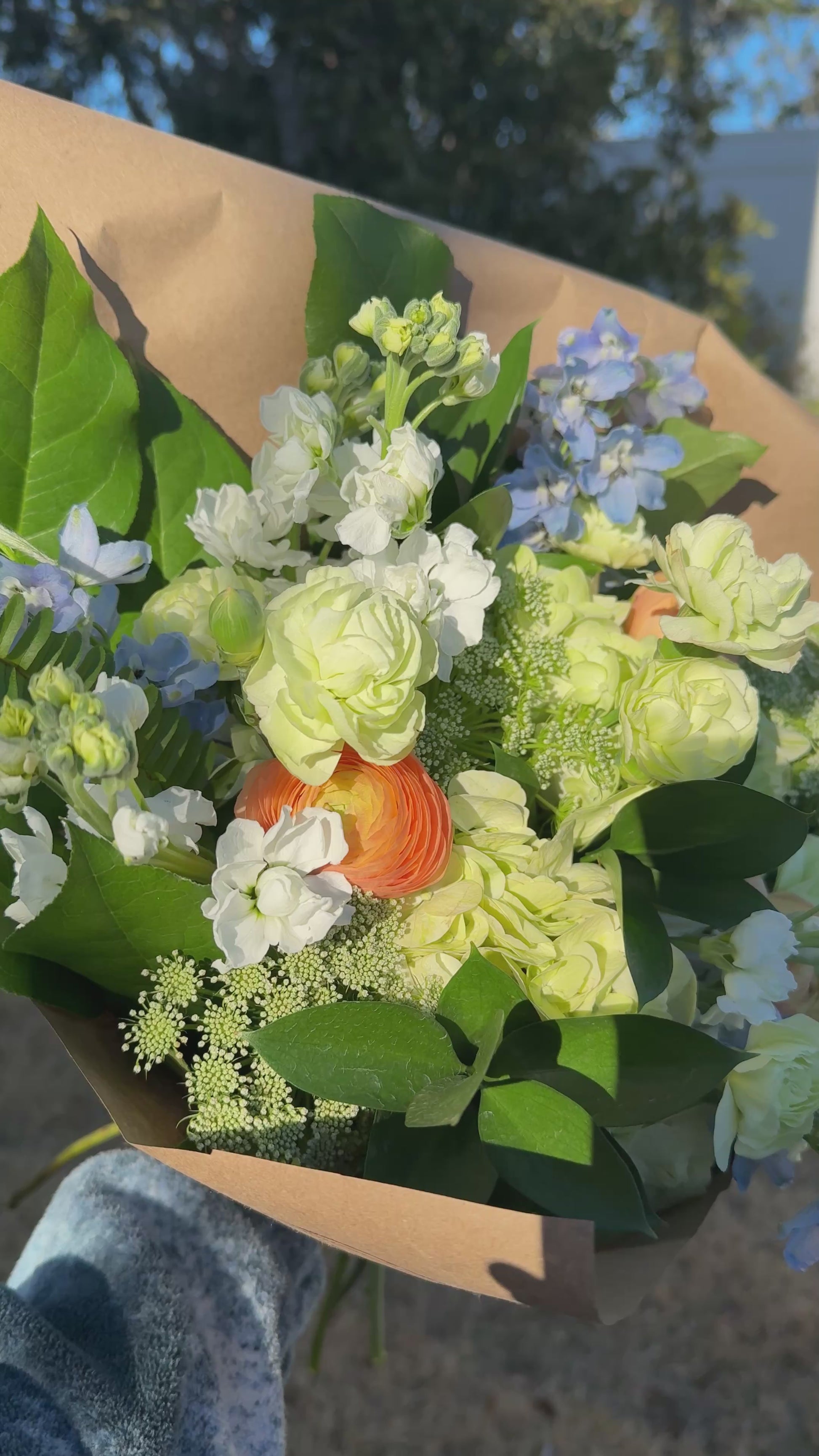 A video of a bouquet of green, white, peach, and blue colored flowers.
